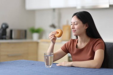 Asyalı kadın mutfaktaki çöreğe bakıyor.