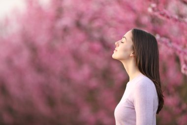 Çiçekli bir bahar tarlasında dinlenen temiz hava soluyan bir kadının profili