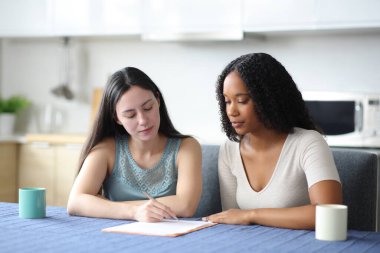 Ciddi ırklar arası oda arkadaşları evdeki mutfakta kontrat imzalıyorlar.