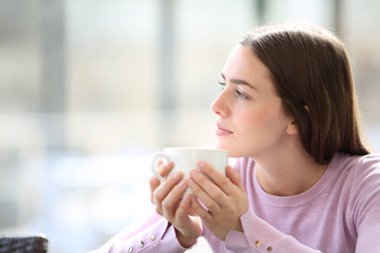 Kahve içen ciddi bir kadın barda oturmuş başka tarafa bakıyor.