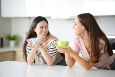 İki arkadaş evde kahve içip sohbet ediyorlar.