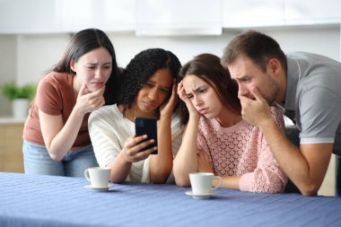 Üzücü ırklar arası arkadaşlar mutfaktaki telefona bakıyorlar.