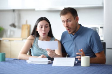 Şaşırmış ırklar arası bir çift evdeki mutfakta banka hesaplarını kontrol ediyor.