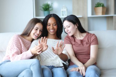 Üç mutlu kadın evdeki kanepede oturan maniküre bakıyor.
