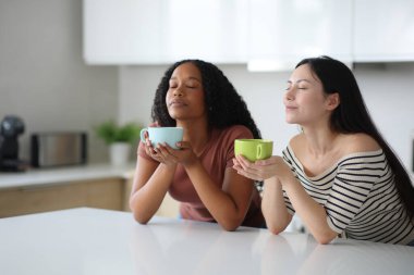 Evdeki mutfakta içen ve nefes alan ırklar arası lezbiyen çift.