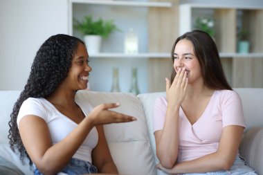 Evdeki bir konuşmada ağzını kapatan kadın gülümsüyor.