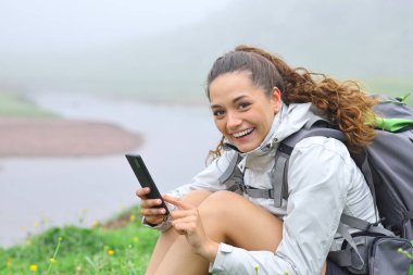 Mutlu yürüyüşçü, dağda oturmuş sana bakıyor.
