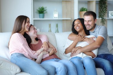 İki mutlu çift evdeki kanepede oturup konuşuyor.