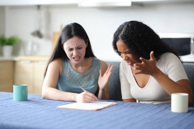 Kızgın ırklar arası oda arkadaşları evdeki mutfakta kağıt sözleşmesi okuyorlar.