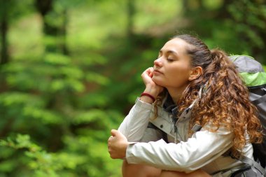 Yürüyüşçü dinleniyor ve gözleri kapalı bir ormanda tek başına oturuyor.