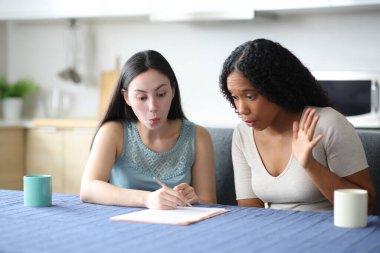 Irklar arası oda arkadaşları evdeki mutfakta kağıt kontratı okuyorlar.