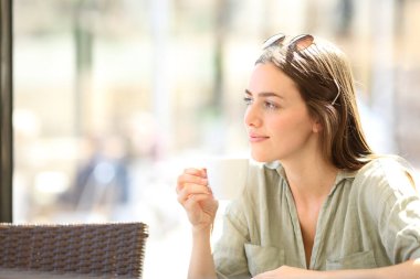 Tatmin olmuş bir kadın bir barda kahve içiyor.