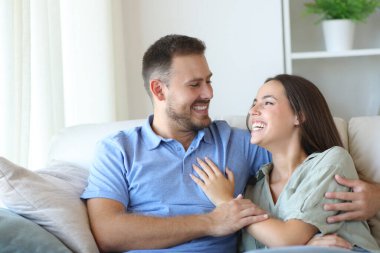 Mutlu çift evde bir kanepede oturuyor.
