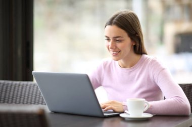 Kahve dükkanında dizüstü bilgisayar kullanan mutlu bir kadın.