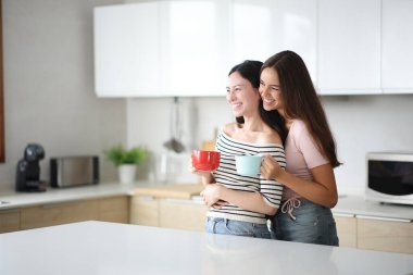 Irklar arası lezbiyen çift kahve içiyor ve evde mutfakta dikilip gözlerini kaçırıyor.