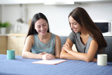 İki mutlu ırklar arası oda arkadaşı evdeki mutfakta kağıt kontratı imzalıyor.