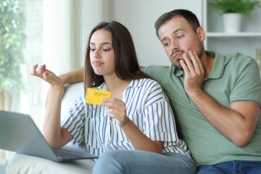 Sıkılmış çift evde kredi kartı ve dizüstü bilgisayarla online ödeme bekleyerek vakit kaybediyor.