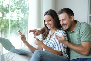 Umut dolu çift evde dizüstü bilgisayar içeriğini kontrol ediyor.