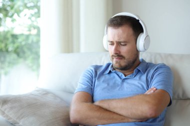 Üzgün adam evdeki bir kanepede oturup internetten müzik dinlemekten şikayetçi.