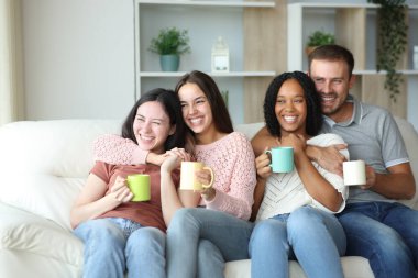 İki farklı ırktan çift kahve içerek evdeki kanepede rahatça oturuyorlar.