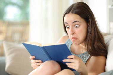 Evdeki kanepede oturmuş kitap okuyan kafası karışık bir kadın.