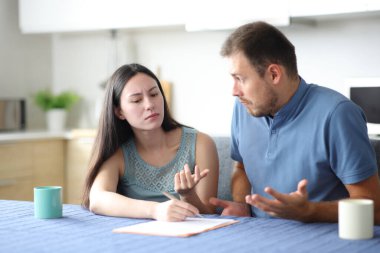 Kızgın kadın evdeki mutfakta kafası karışmış ortağına açıklama istiyor.