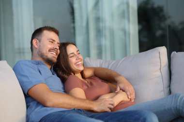 Mutlu çift evde ya da otel odasındaki bir kanepede oturup terasta eğleniyor.