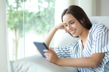 Mutlu kadın evin içindeki bir kanepede oturmuş kitap okuyor.