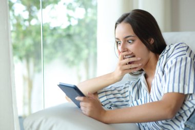 Şaşırtıcı bir şekilde kitap okuyan kadın evdeki kanepede oturuyor.