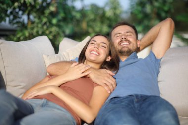 Mutlu çift evdeki kanepede uzanmış terasta dinleniyor.