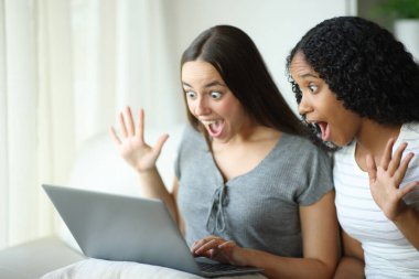 İki ırklar arası oda arkadaşı evdeki kanepede oturup laptoptan şaşırtıcı haberleri kontrol ediyor.