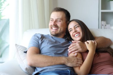 Mutlu çift gülüyor. Evdeki kanepede oturuyor.