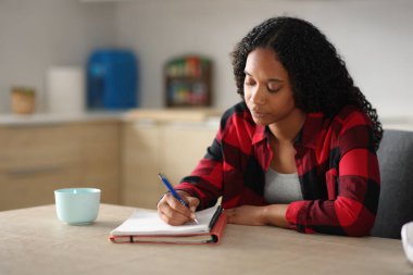Yoğunlaşmış siyahi öğrenci evde mutfakta not yazmayı öğreniyor.