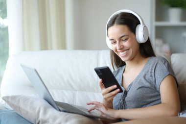 Evdeki koltukta oturan, kulaklık takan mutlu bir kadın.