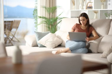 Evdeki oturma odasında dizüstü bilgisayar kullanan bir kadın.