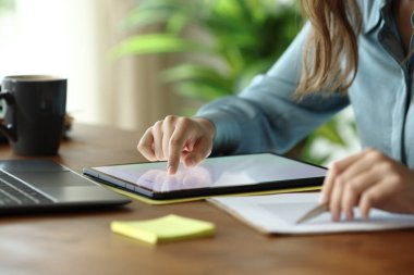 Tablet üzerinde kaydırma yapan bir ofis çalışanının portresini kapat. Tahta masadaki belgelerin istatistiklerini kontrol et.