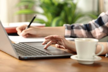 Öğrencilerin ellerini kapat dizüstü bilgisayarı kontrol et ve evdeki tahta masaya not al.