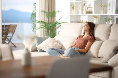 Mutlu kadın kanepede oturup evdeki pencereden bakıyor.