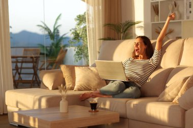 Heyecanlı kadın internette iyi haberleri kutluyor. Gün batımında kollarını kaldırıyor.