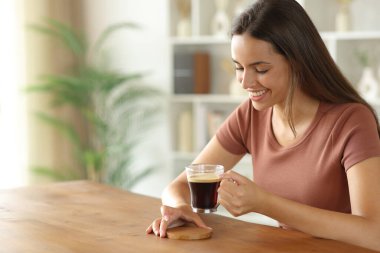 Evdeki ahşap bir masanın üzerine bardak altlığı koyan mutlu kadın.