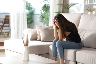 Üzgün kadın evin içindeki bir kanepede tek başına oturmaktan şikayetçi.