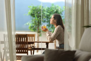 Evde terasta oturmuş çay kokusu alan bir kadının profili.