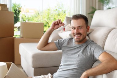 Evin anahtarlarını taşıyan mutlu kiracı seni yerde otururken izliyor.