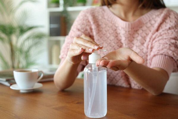 Закрыть руки женщины, наносящей гидроалкогольный гель на деревянный стол дома