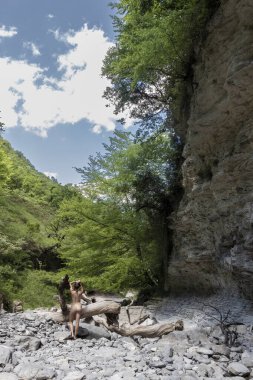 Naked girl alone outdoor on top on a mountain with the beautiful view of the hills and woods.