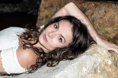 Geceleri sahilde kayalıklarda yatan bir kadın.