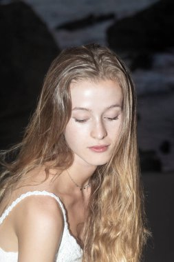 Gün batımında plajda poz veren seksi mayo giymiş güzel sarışın bir kadının portresini yakından çek..