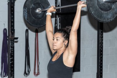 Genç Latin kadın Crossfit spor salonunda ağırlık kaldırıyor.