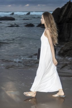 Kumsalda dizüstü bilgisayar kullanan genç bir kadın. Serbest çalışma kavramı