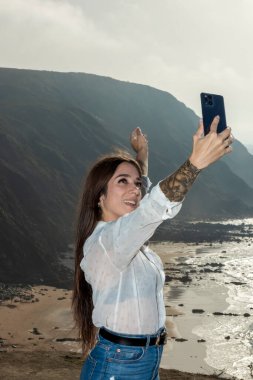 woman taking a selfie while standing on the seacoast